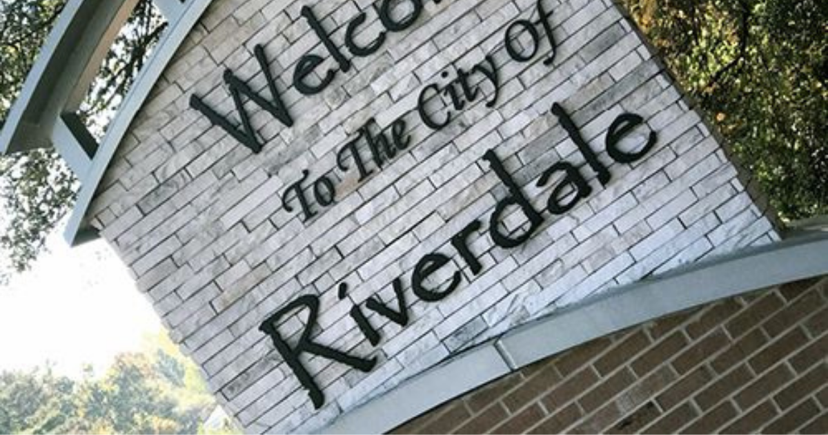 Technician kneeling beside a sprinkler repair in Riverdale
